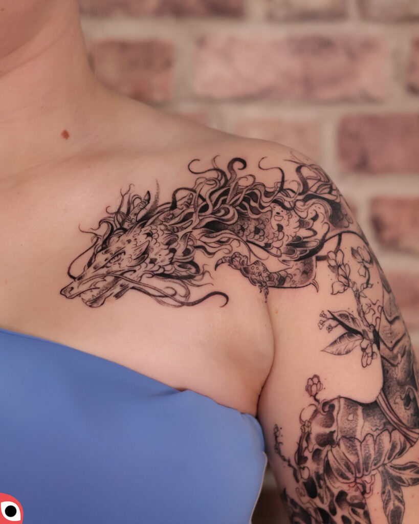 tatuaż smok chiński ozdobny kwiaty magnolie ramię graficzny czarny duży